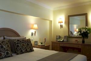 Schlafzimmer im Atlantica Imperial Resort mit Bett, Nachttisch, Spiegel und Deko.