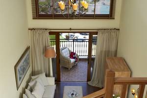 Innenansicht eines Wohnzimmers mit Balkon im Atlantica Imperial Resort & Spa, das eine weiße Couch, ein Beistelltischchen, eine Lampe und ein Fenster zeigt.