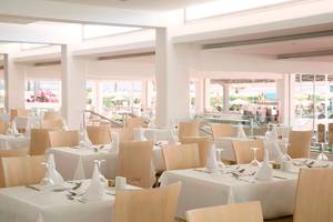 Restaurant im Asterias Beach Hotel mit gedeckten Tischen und Blick auf den Strand