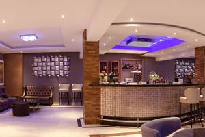 Innenansicht der Bar im Asterias Beach Hotel mit modernen Möbeln und violetten Akzenten.