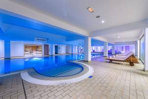 Innenpool des Asterias Beach Hotels mit blauen Lichtern und Liegestühlen.