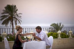 Ein Paar genießt ein romantisches Essen auf einer Terrasse mit Blick auf das Meer im Atlantica Imperial Resort & Spa.