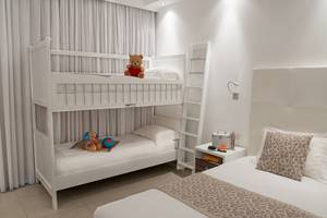 Ein Schlafzimmer mit einem weißen Etagenbett, einem Teddybär und einem Schlafsofa.