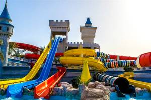Wasserpark des Serenity Alma Heights Hotels mit bunten Rutschen und Burg im Hintergrund