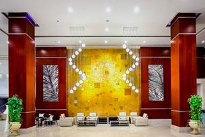 Lobby des Serenity Alma Heights Hotels mit gelber Wand, Kronleuchtern und Möbeln.