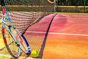 Tennisschläger neben einem Tennisball auf einem Tennisplatz.