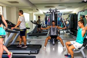 Fitnessstudio im Serenity Alma Heights Hotel mit Personen, die an Geräten trainieren.