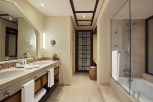 Badezimmer im Salalah Rotana Resort mit zwei Waschbecken, Dusche und Badewanne.