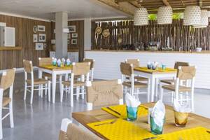 Innenbereich des Zilwa Attitude Hotels mit weißen und gelben Tischen, braunen Stühlen und Holzwänden.