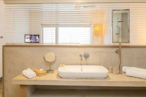 Ein Badezimmer im Zilwa Attitude Hotel mit einer weißen Wanne, Handtüchern, einem Spiegel und einer Fensterbank.