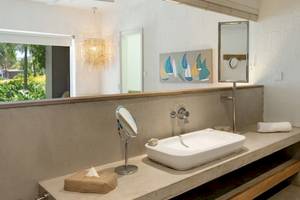 Badezimmer im Zilwa Attitude Hotel mit Spiegel, Waschbecken und Fenster.