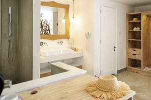 Badezimmer im Zilwa Attitude Hotel mit weißem Waschbecken, Spiegel und Holzschrank.