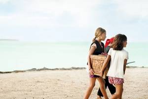 Kinder am Strand tragen Piratenkostüme und tragen einen Holzkasten.