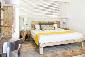 Ein modernes Hotelzimmer im Zilwa Attitude mit weißem Bett, gelber Decke, Holzbettrahmen, Nachttischen und Wanddekoration.