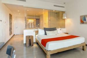 Ein modernes Hotelzimmer im Zilwa Attitude Hotel mit einem Bett, Kissen, Decken und einer Wanddekoration.