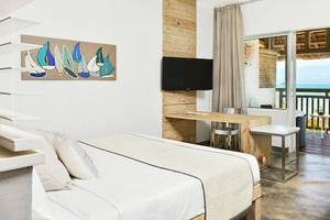 Ein modernes Hotelzimmer mit einem Bett, Schreibtisch, Fernseher und einem Balkon mit Meerblick.