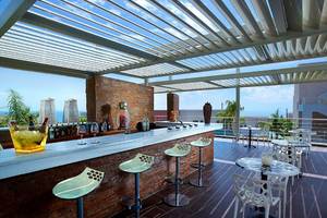 Bar-Terrasse im Michelangelo Resort & Spa mit Tischen, Stühlen und einer Aussicht auf das Meer.