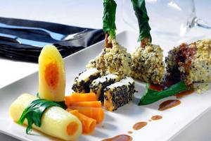 Elegantes Gericht im Michelangelo Resort & Spa mit Sushi, Karotten, Kartoffeln und Soße.