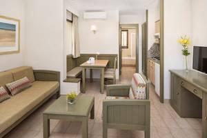 Innenansicht einer Suite im HD Parque Cristobal Hotel mit Wohnzimmer, Essbereich und Fernseher.
