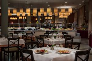Foto des Innenbereichs des Restaurants im HD Parque Cristobal Hotel mit gedeckten Tischen und Buffet.