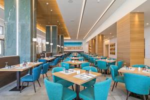 Innenraum des Restaurants im Amada Colossos Resort mit blauen Stühlen und Holztischen.
