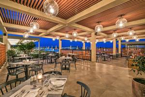 Abendessen im Hotelrestaurant des Amada Colossos Resort mit Tisch, Stühlen und hängenden Lampen.