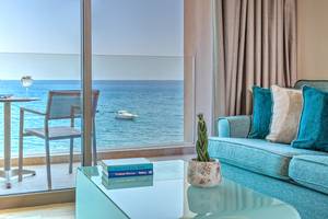 Hotelzimmer mit Meerblick: Couch, Tisch und Bücher auf dem Glastisch.