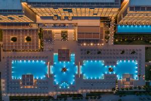 Ein abendlicher Blick auf das Amada Colossos Resort mit mehreren Schwimmbecken und Beleuchtung.