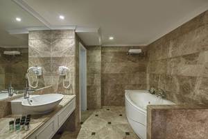 Badezimmer im Delphin Diva Premiere Hotel mit Badewanne und Waschbecken.