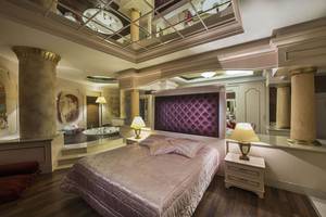 Schlafzimmer im Delphin Diva Premiere Hotel mit Bett, Nachttischen, Lampen und Badewanne