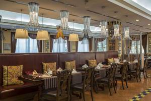 Innenansicht des Restaurants im Delphin Diva Premiere Hotel mit gepolsterten Bänken und Holztischen.