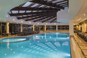 Innenpool des Delphin Diva Premiere Hotels mit Liegestühlen und Glasdach.