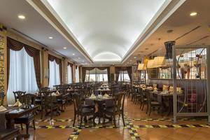 Innenansicht des Restaurants im Delphin Diva Premiere Hotel mit runden Tischen, Stühlen und dekorativen Wandmustern.