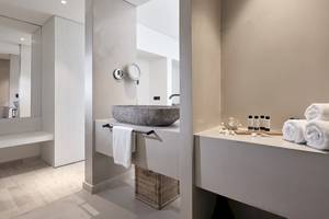 Ein elegantes Badezimmer des Caravel Hotels mit einem großen Steinwaschbecken und einem Spiegel.