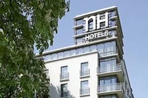 Außenansicht des NH Berlin Alexanderplatz Hotels mit grünen Bäumen und Berliner Fernsehturm.