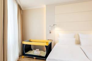 Hotelzimmer im NH Berlin Alexanderplatz mit zwei Betten und einem Kinderbett