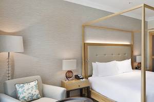 Ein elegantes Hotelzimmer im Hilton Cabo Verde Sal Resort mit einem Himmelbett, einer Kommode und einem Badezimmer.
