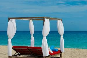 Liegestuhl auf dem Strand des Hilton Cabo Verde Sal Resorts mit Blick auf das Meer.