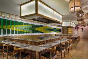 Innenansicht des Restaurants H10 Lanzarote Princess mit grünen und gelben Wandmustern, Holztischen und Stühlen.