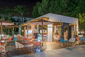 Außenbereich des H10 Lanzarote Princess Hotels bei Nacht mit bunten Stühlen und Tischen.