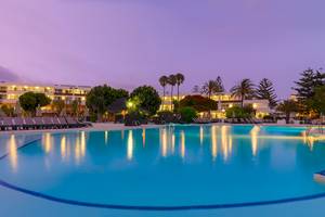 Außenpool des H10 Lanzarote Princess Hotels bei Nacht mit Lounge-Stühlen und Palmen im Hintergrund.