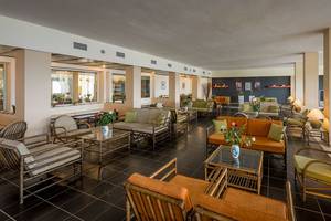 Lobbybereich des Pavlina Beach Hotels mit Möbeln und Blumenarrangements.