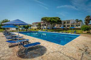 Außenpool des Pavlina Beach Hotels mit Sonnenliegen und Sonnenschirmen.
