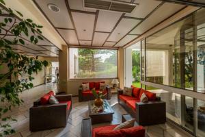 Lobby-Lounge im Pavlina Beach Hotel mit roten Sofas, Glaswänden und Pflanzen.