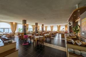 Innenansicht des Restaurants im Pavlina Beach Hotel mit Tischen, Stühlen und Meeresblick.