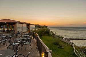 Terrasse des Pavlina Beach Hotels mit Blick auf das Meer bei Sonnenuntergang.