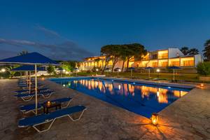 Abendlicher Blick auf den Pool im Pavlina Beach Hotel mit blauen Sonnenschirmen und Lounge-Liegestühlen.
