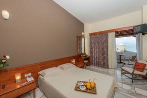 Hotelzimmer im Pavlina Beach Hotel mit Balkon und Meerblick, einschließlich Bett, Frühstückstablett, Tisch und Fernseher.