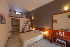 Ein Schlafzimmer im Pavlina Beach Hotel mit zwei Betten, einer Treppe und einem Balkon.