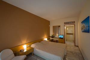 Doppelzimmer im Pavlina Beach Hotel mit zwei Betten, Fernseher, Tisch, Stuhl und Spiegel.